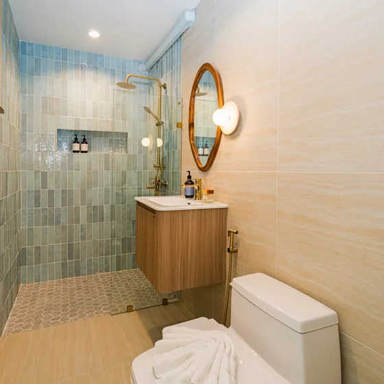 Blue green tiled shower with a brass rain head