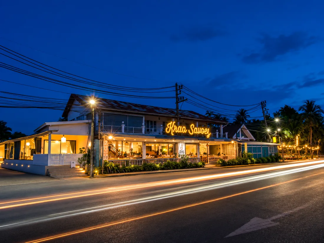 Krua Savoey lit up at night, seen from across the coastal road